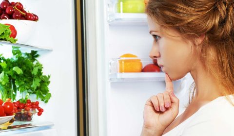 Kind schaut in einen Kühlschrank und fragt sich, was es essen soll