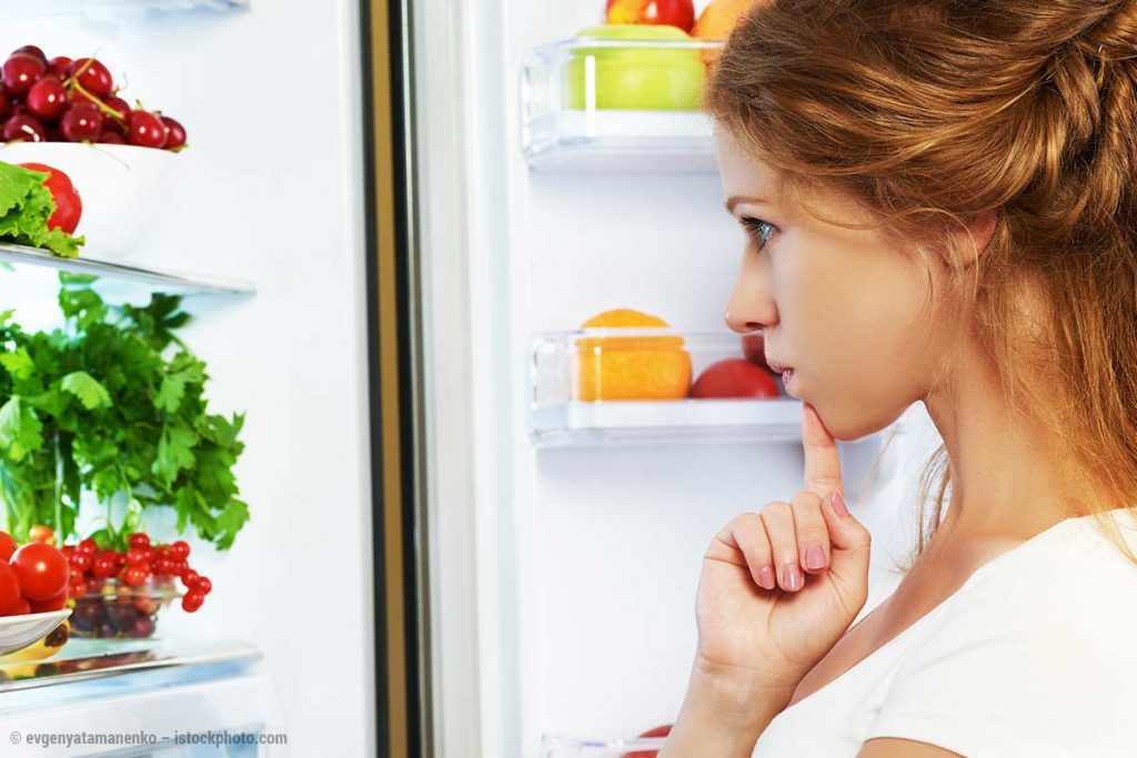 Kind schaut in einen Kühlschrank und fragt sich, was es essen soll